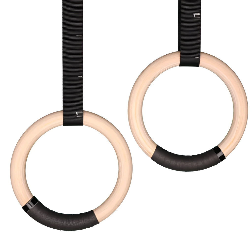 Birch wood gymnastics rings with nylon straps on a pull-up bar in a home gym setting