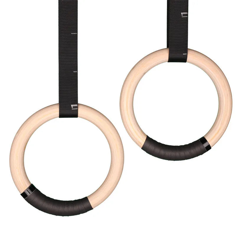 Birch wood gymnastics rings with nylon straps on a pull-up bar in a home gym setting