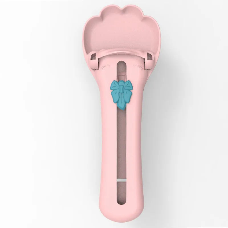 Green and pink pet food squeezer scoop dispensing a treat for a cat or dog.