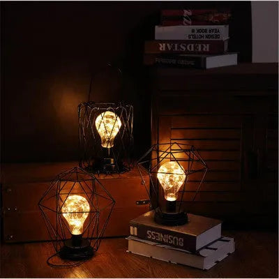 Minimalist hollow iron table lamp in red wine glass style on a wooden desk.