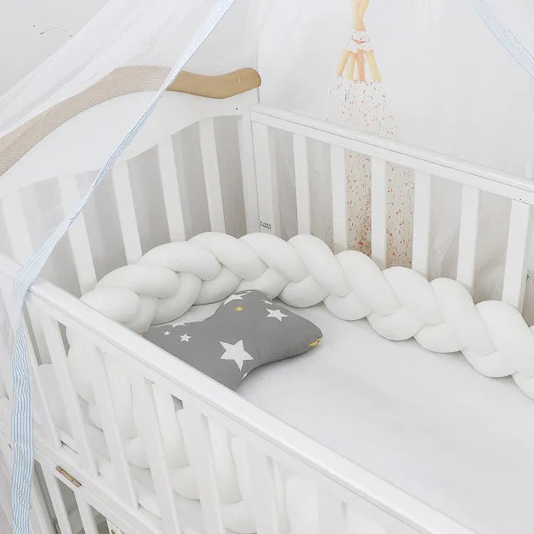Braided knot baby crib bumper in spandex velvet wrapped around white cot rails.