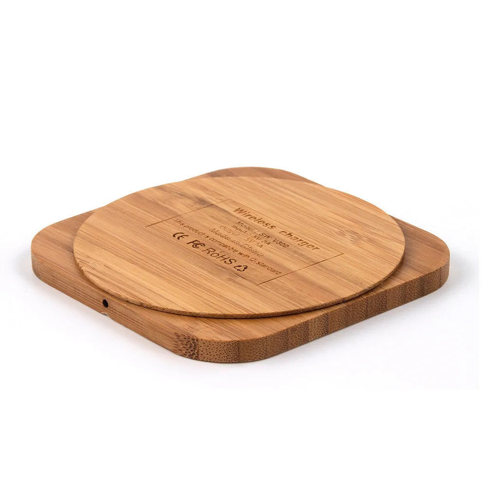 Square wooden bamboo 5W Qi wireless charging pad on a desk next to a smartphone.