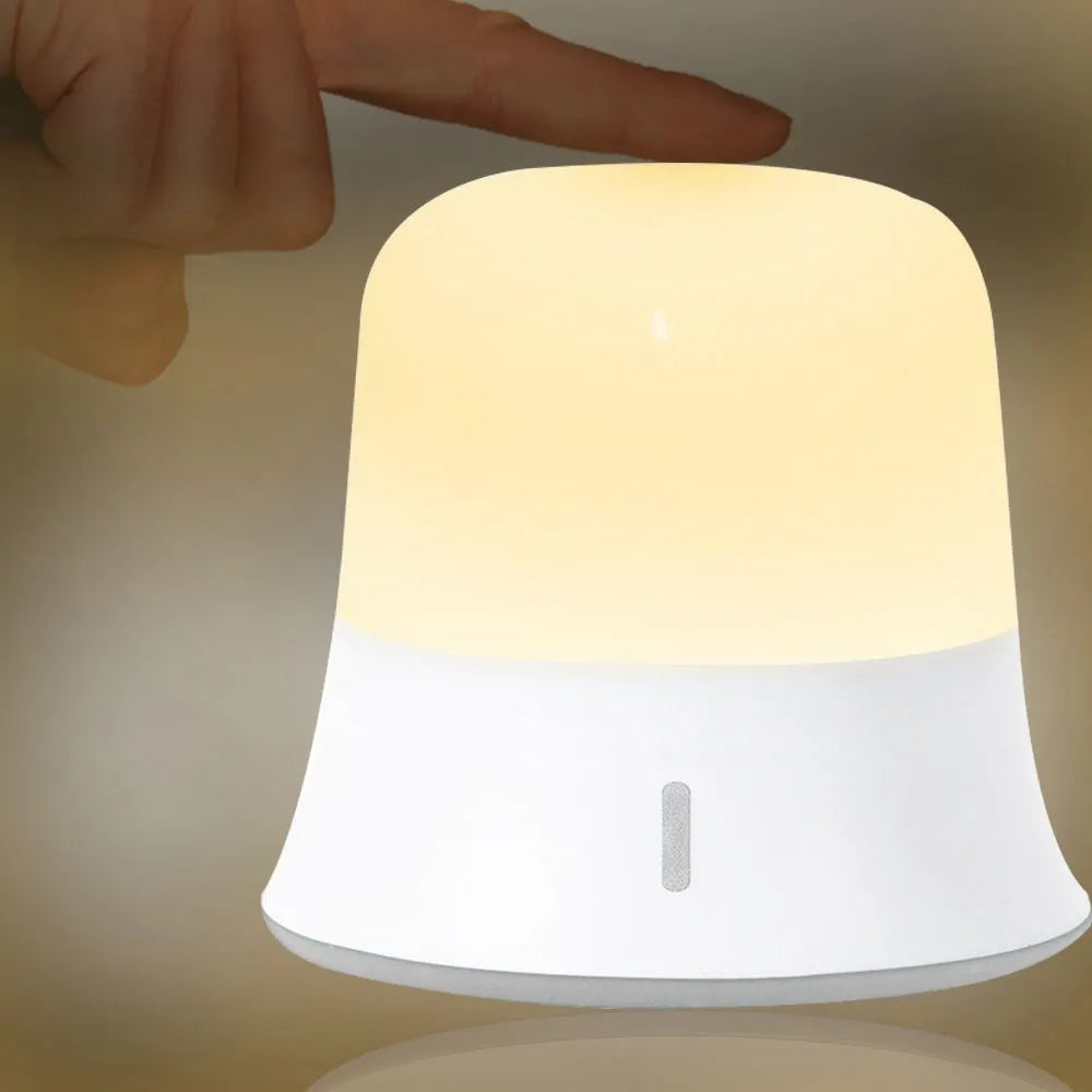 White touch-control bedside night light with motion sensor and rechargeable battery on a table.
