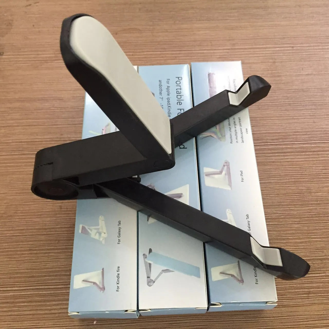 Black foldable aluminium tablet holder open in landscape mode supporting an iPad, showing side adjustment buttons.
