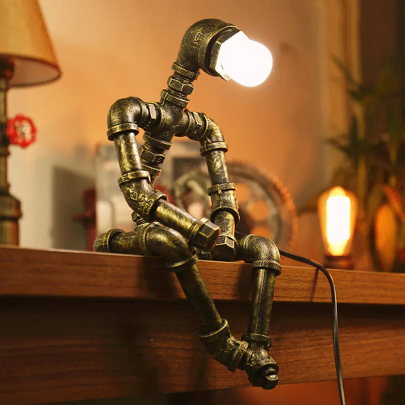 Green bronze vintage industrial iron pipe desk lamp on a wooden table.