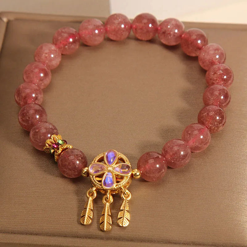 Women's strawberry quartz crystal bracelet with a four-leaf clover dream catcher ball pendant.