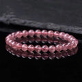 Women's strawberry quartz crystal bracelet with polished round beads on a white background.