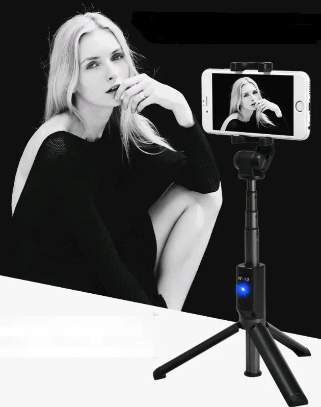 Aluminium Bluetooth selfie stick with tripod base and remote control next to a smartphone.