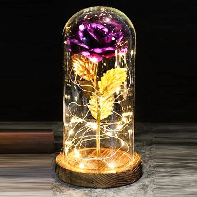 Simulated pink silk rose inside a glass dome with glowing LED fairy lights