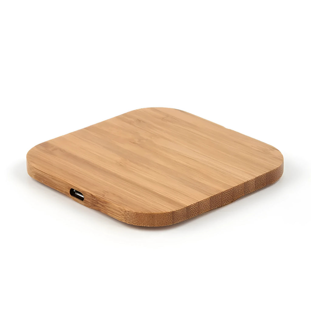 Square wooden bamboo 5W Qi wireless charging pad on a desk next to a smartphone.