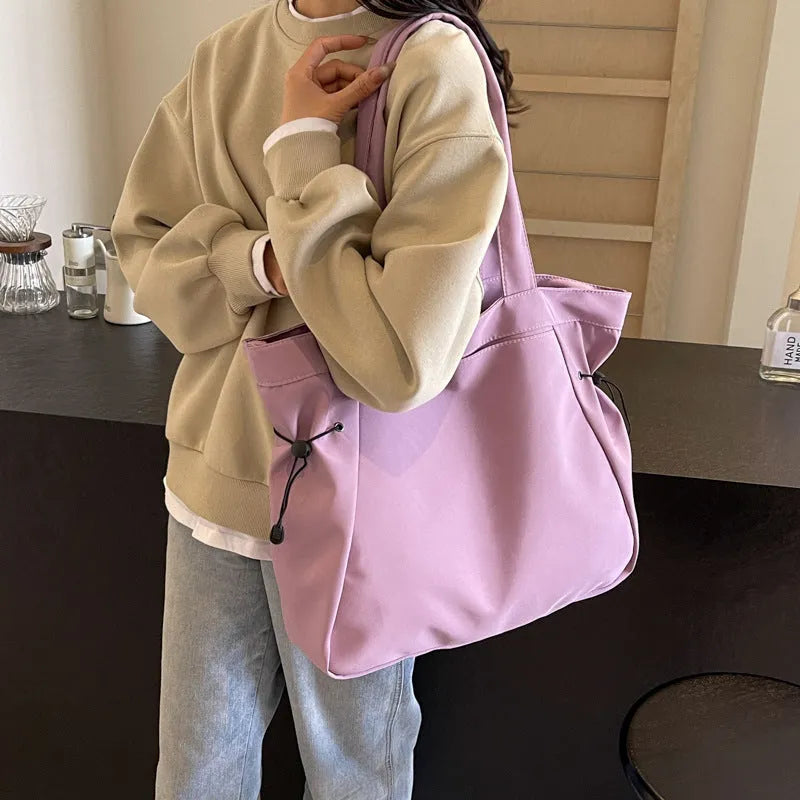 Soft folding shoulder tote bag in Oxford cloth shown in one of five colour options: black, brown, dark grey, light grey, or purple.