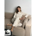 Women's white floral print suit set featuring a round neck top with bell sleeves and wide leg trousers.