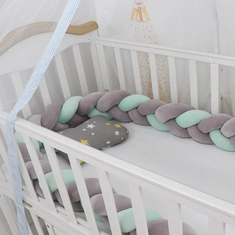Braided knot baby crib bumper in spandex velvet wrapped around white cot rails.