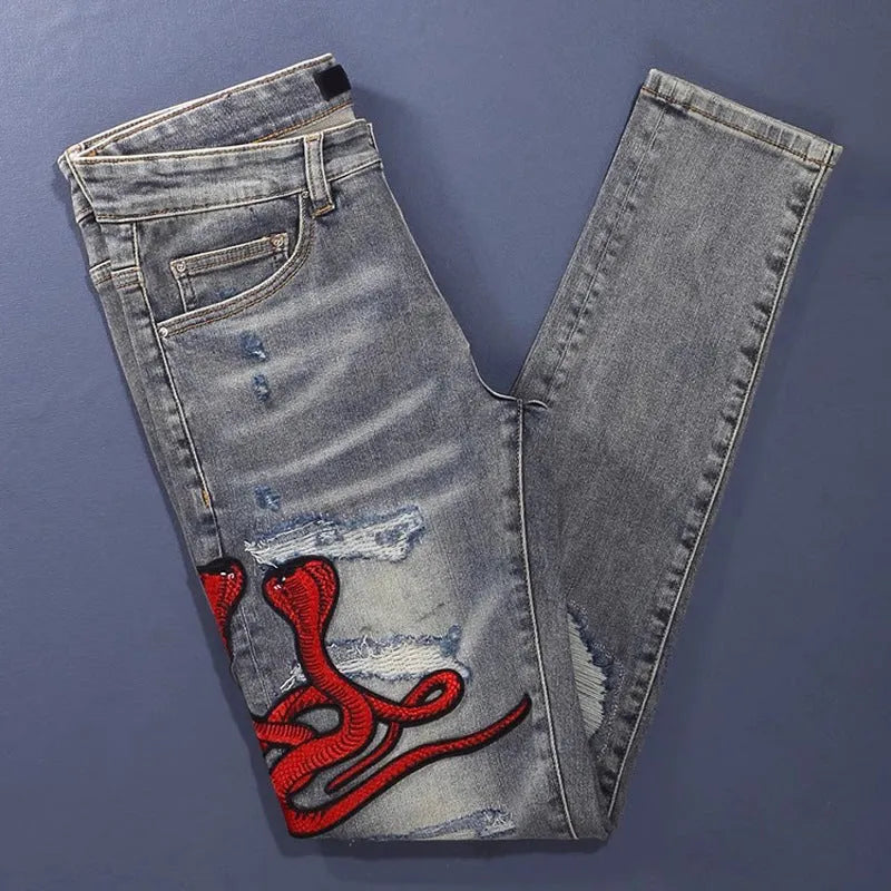 Worn looking washed-out slim fit jeans with hole patches and embroidered brand detail in old colour