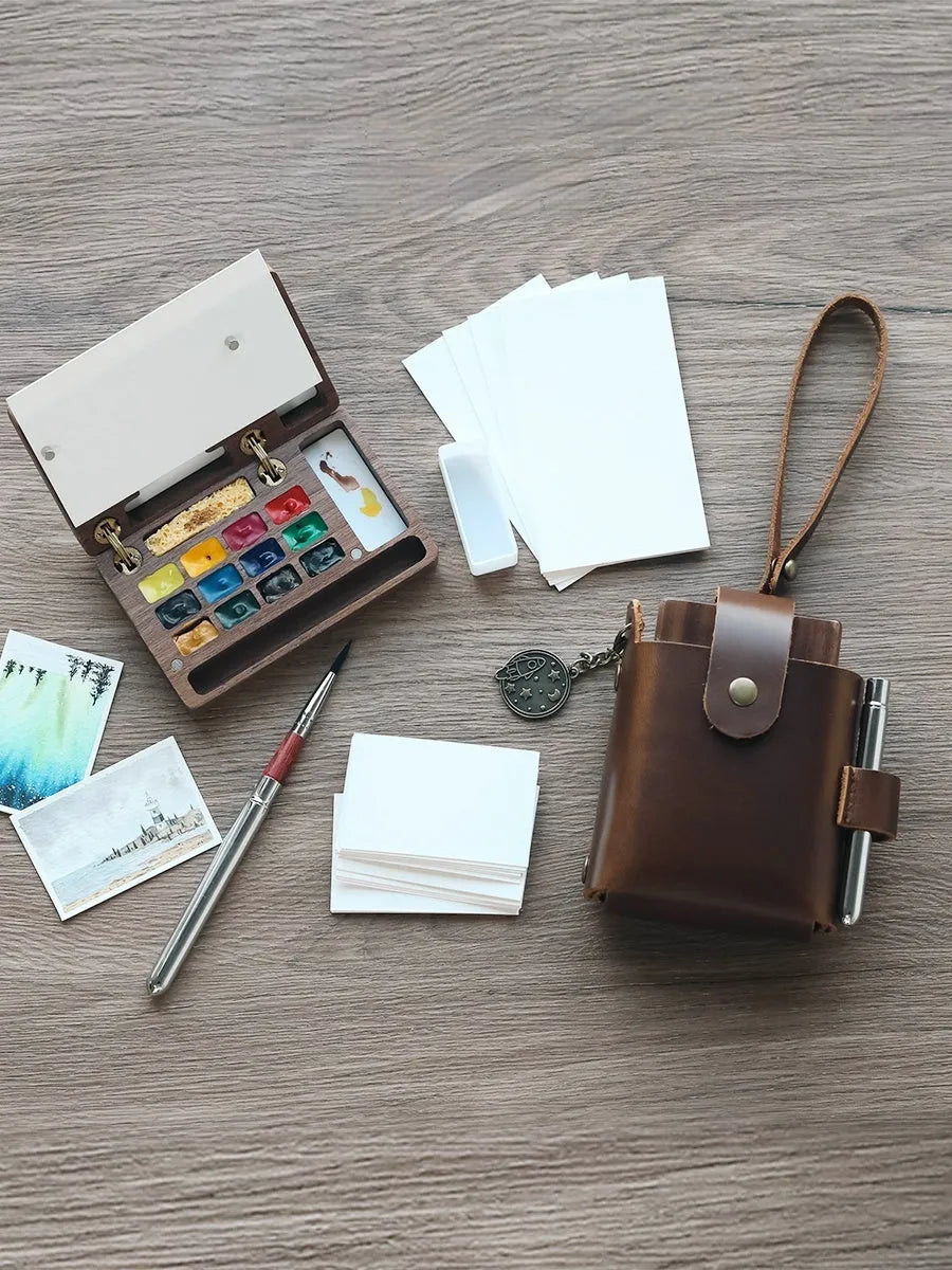 Miniature walnut wood watercolour paint box open to show pigment pans and wooden palette