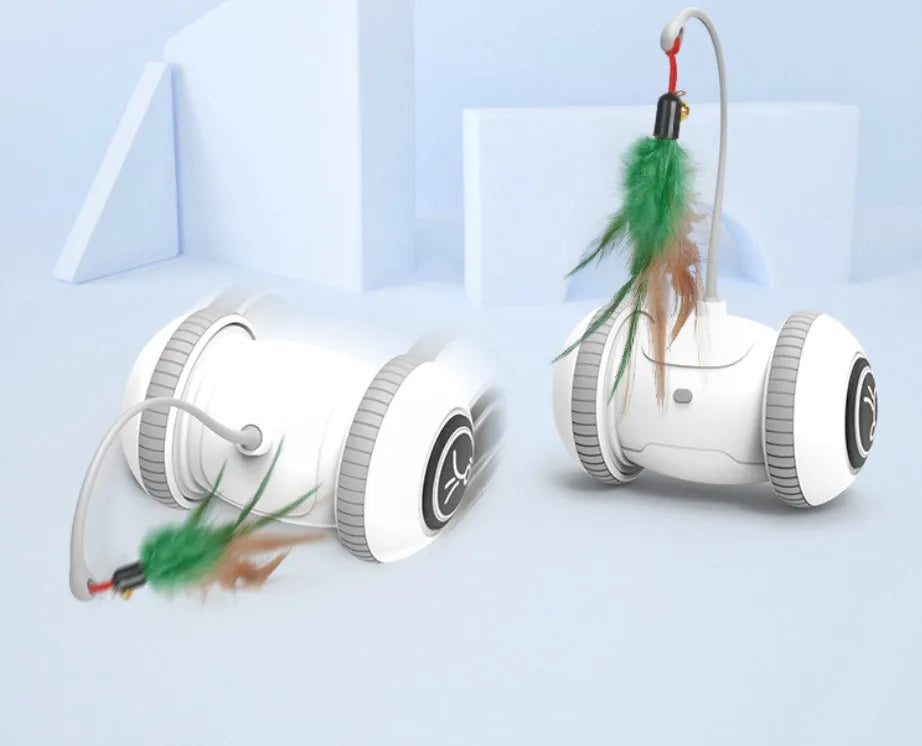 White and grey automatic interactive cat toy with interchangeable feather accessory on a floor, USB cable attached