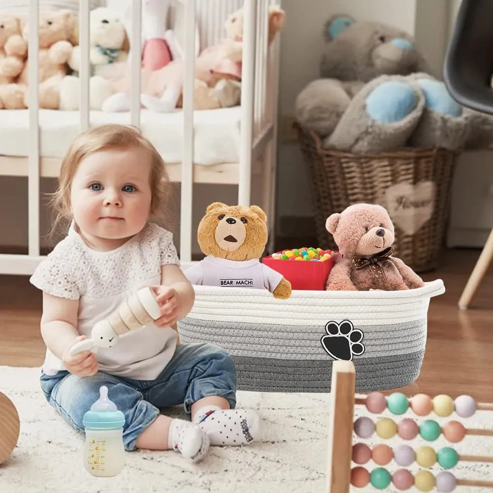 Light beige handmade woven cotton rope storage basket with wooden base and handle on a table.