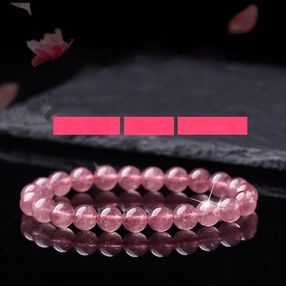 Women's strawberry quartz crystal bracelet with polished round beads on a white background.