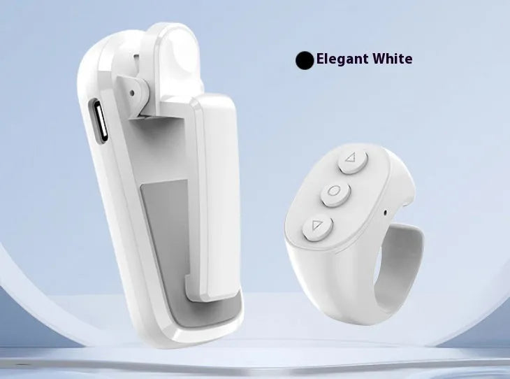 A black wireless page turner remote control and a separate clicker unit on a wooden desk.