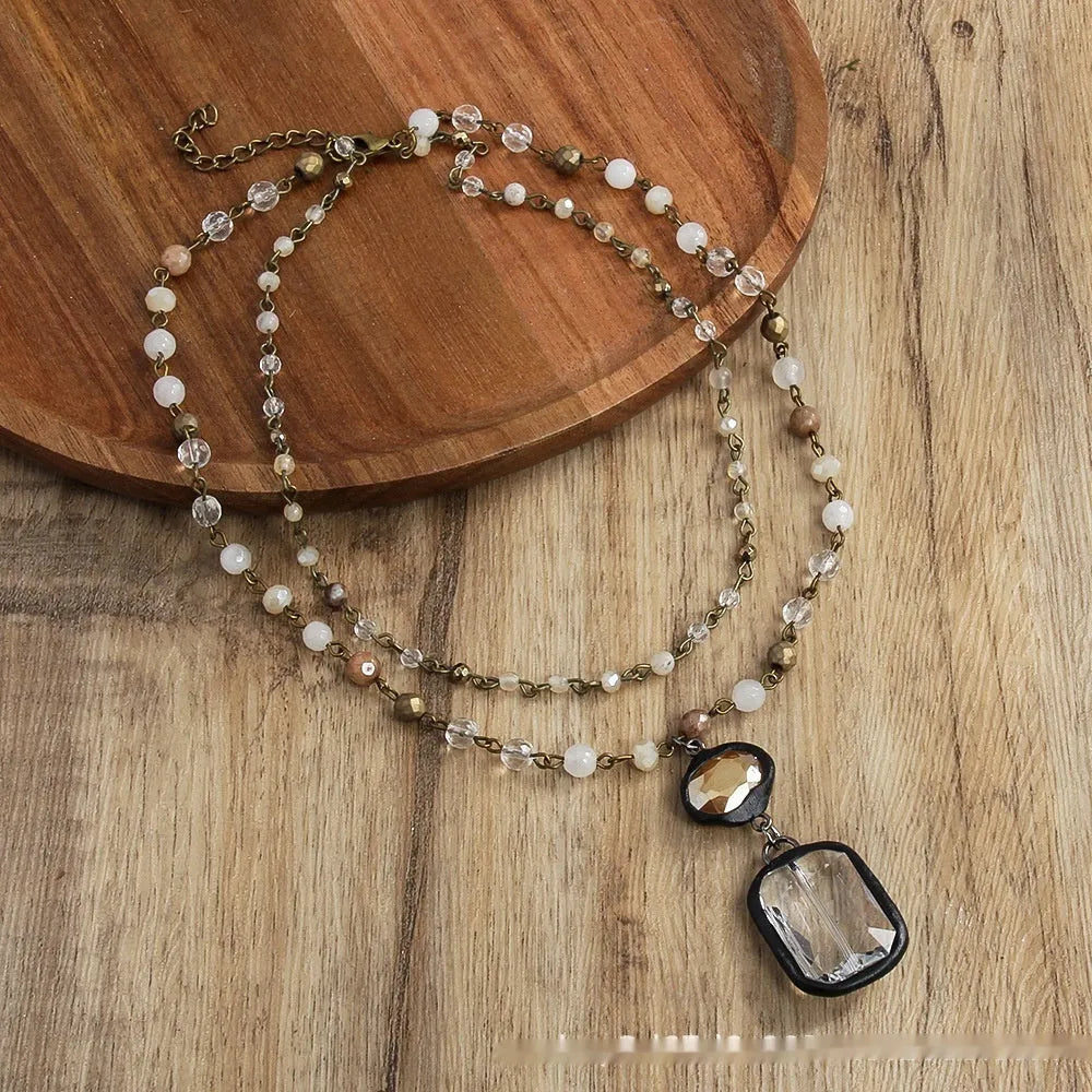 Two-layer tribal necklace with stone and glass pendants on a chain, shown in beige and blue.