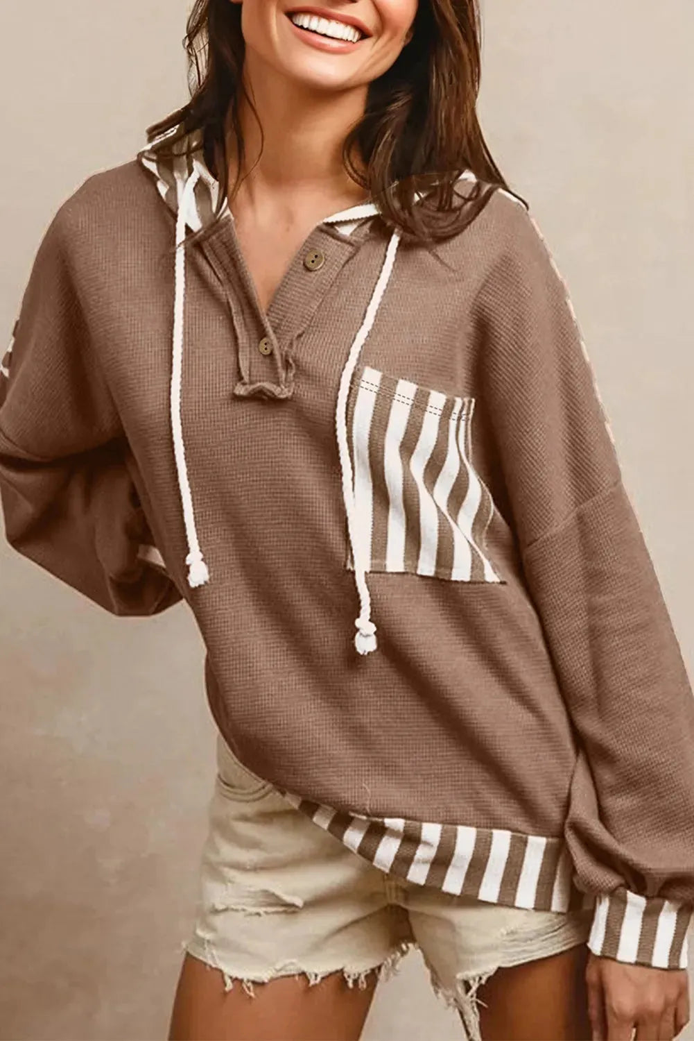 Straw yellow hoodie with waffle texture and striped patchwork design, featuring a button neck and drawstring hood.