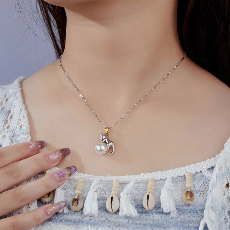 Close-up of a sterling silver cat charm clavicle chain necklace on a model.