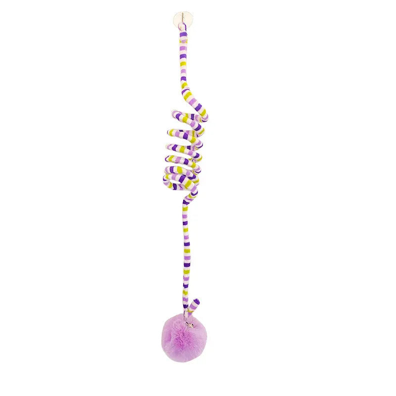 Hanging cat toy with bell stick and red inflatable ball attached to a glass door by a suction cup.