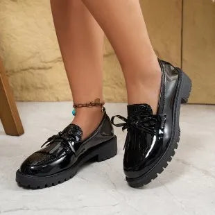 Brown women's slip-on loafers with a black bow detail on the front.