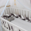 Braided knot baby crib bumper in spandex velvet wrapped around white cot rails.