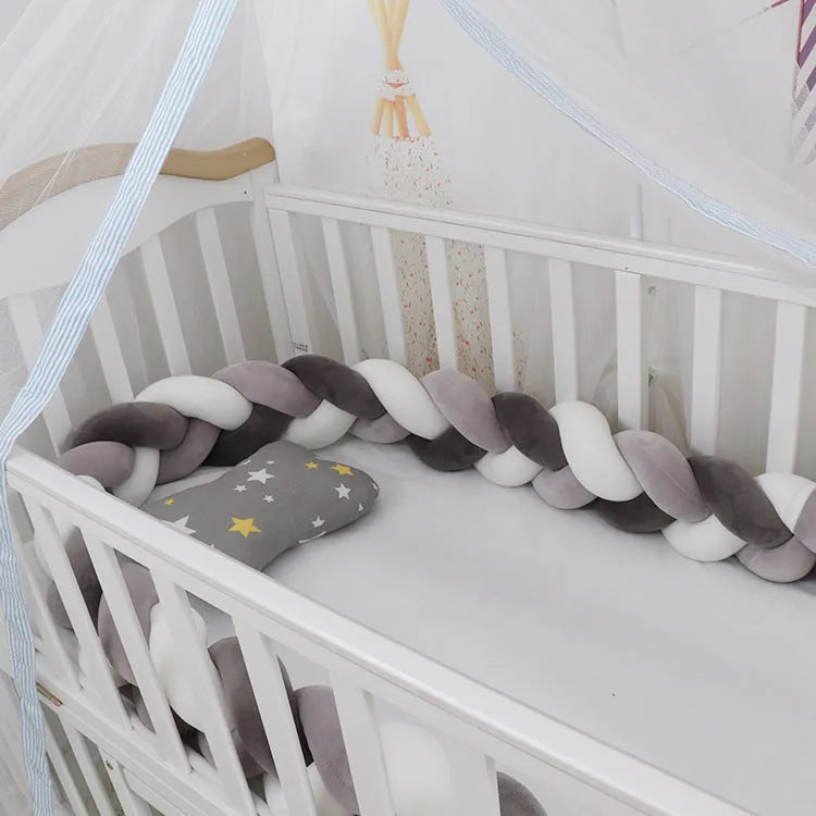Braided knot baby crib bumper in spandex velvet wrapped around white cot rails.