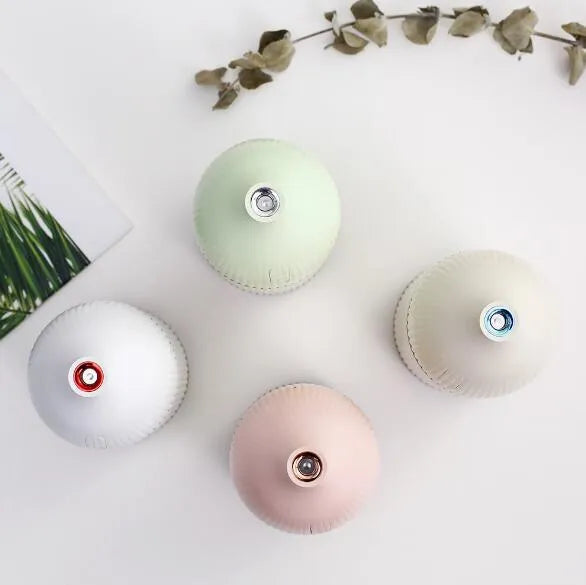 White ultrasonic aromatherapy diffuser with LED light and USB cable on a wooden table