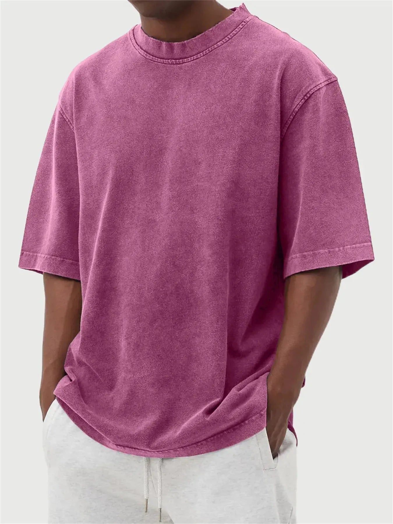 Man wearing a loose-fit, stone-washed grey t-shirt with a distressed solid colour finish and half sleeves.