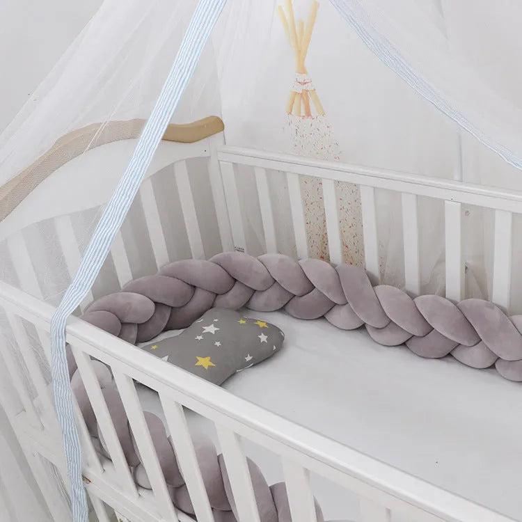 Braided knot baby crib bumper in spandex velvet wrapped around white cot rails.