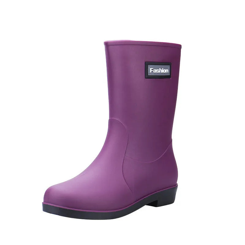 Women's mid-calf PVC rain boot in black on a wet surface, showing low heel and clean design.
