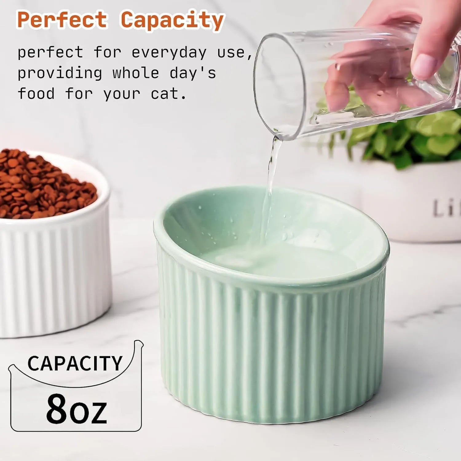 A dark green ceramic elevated cat bowl on a wooden surface, showing its tilted, round shape.