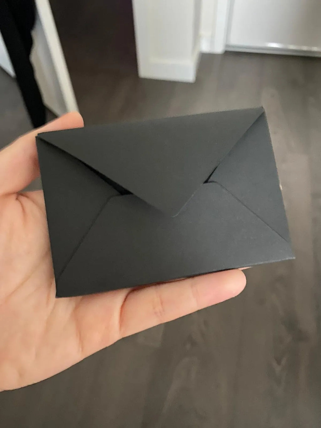 Plain black mailing envelope measuring 9 cm by 6 cm, shown flat with a flap