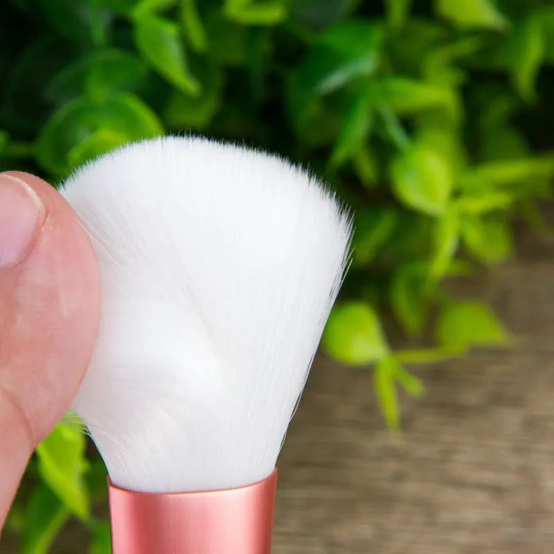 12 pink makeup brushes with synthetic hair bristles and plastic handles on a light surface