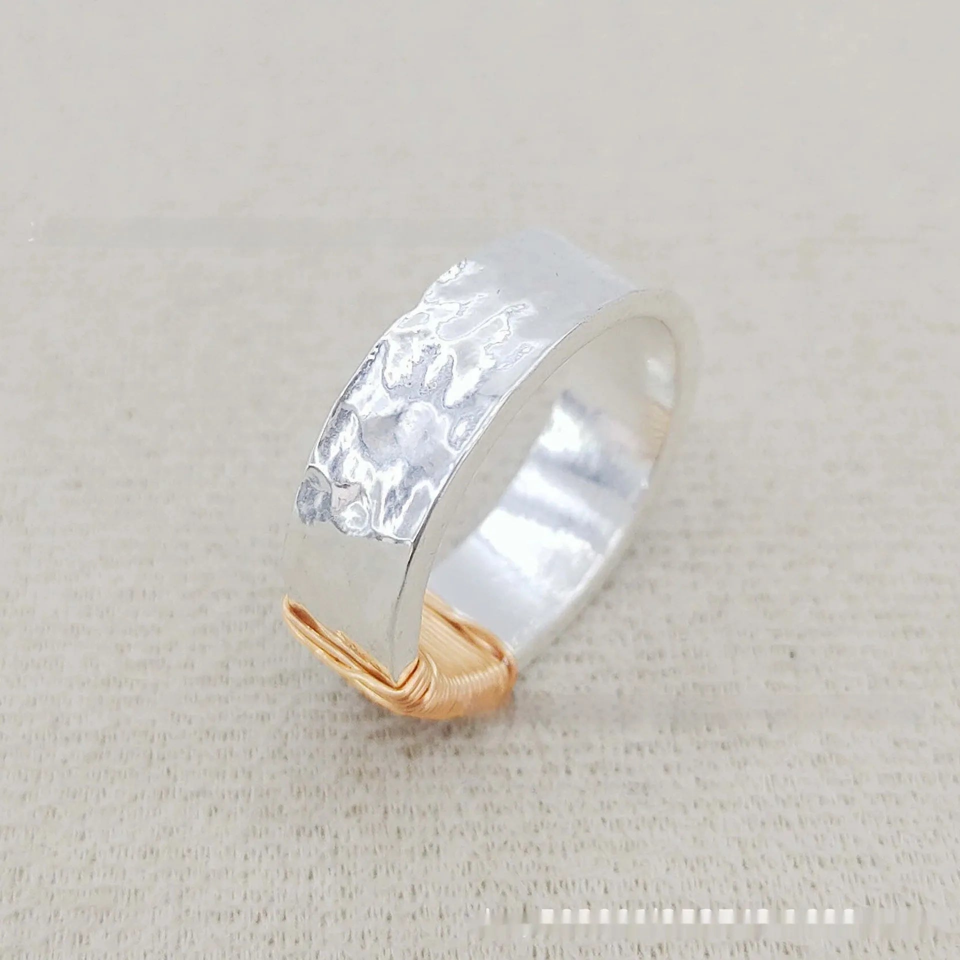 Geometric copper bracelet with irregular coil pattern forming silver-gold wide-faced ring design