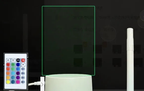 Black 3D LED handwritten acrylic message board with remote control on a desk.