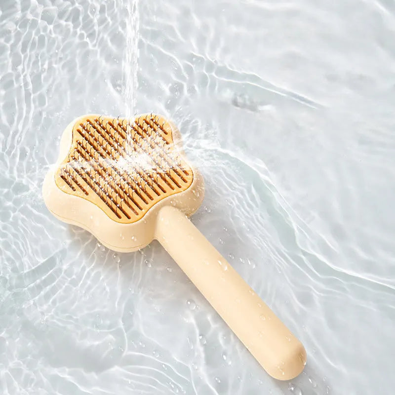 Green and yellow self-cleaning cat grooming comb with stainless steel needles on a white background.