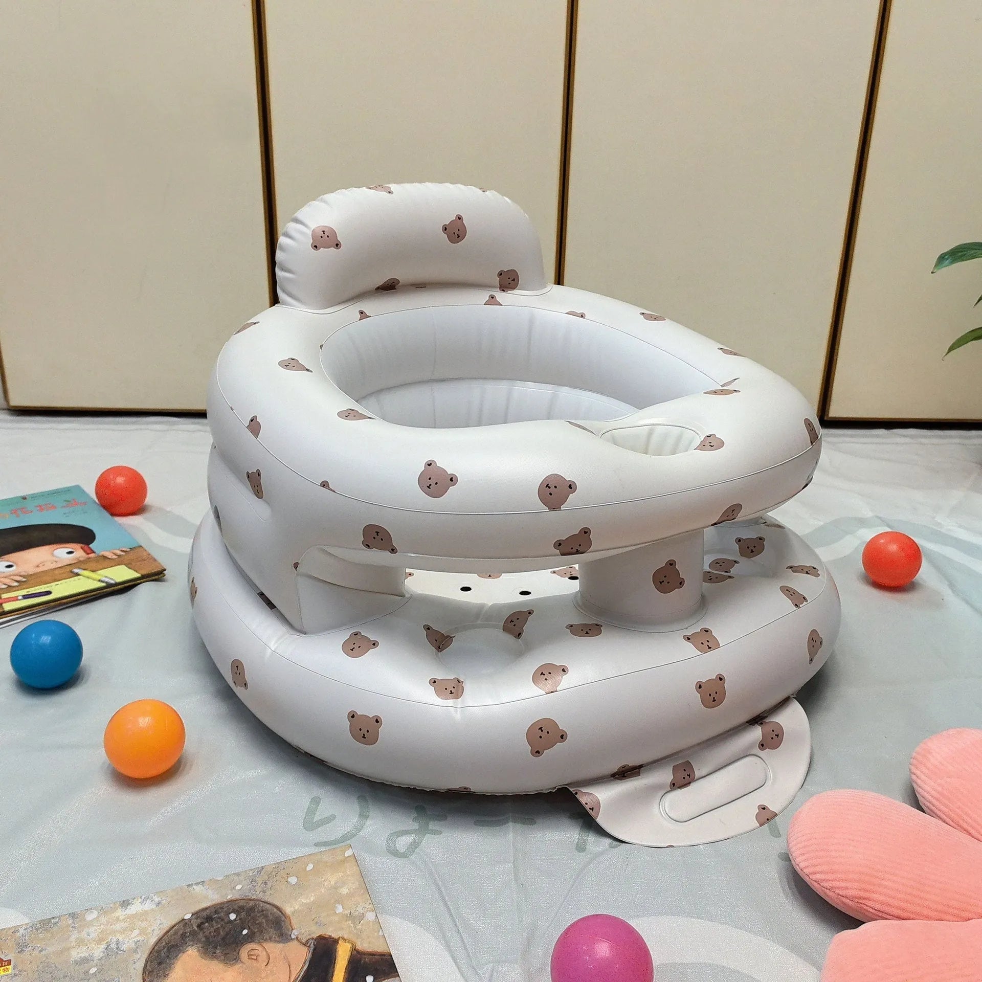 Inflatable infant dining chair in PVC with bear design, deflated beside a baby for scale