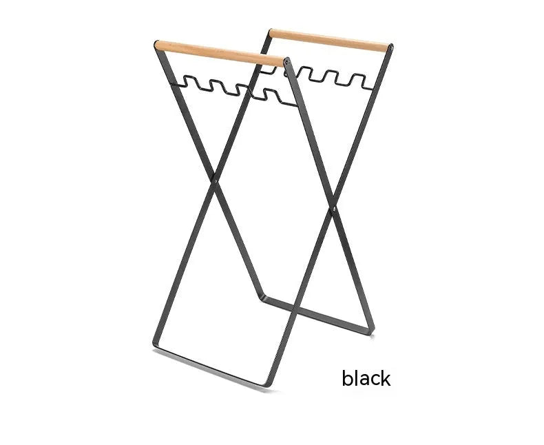 Black iron folding trash storage rack with wooden handle mounted on a wall.