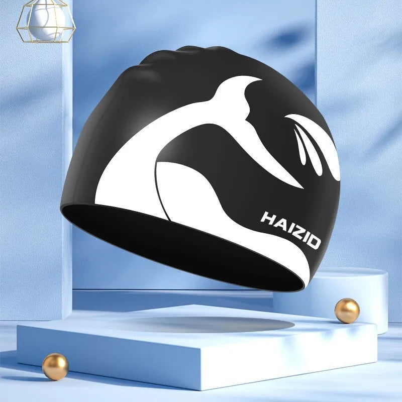 Silicone swimming cap with whale tail pattern and built-in ear protectors in assorted colours.