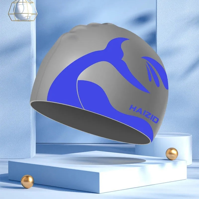 Silicone swimming cap with whale tail pattern and built-in ear protectors in assorted colours.