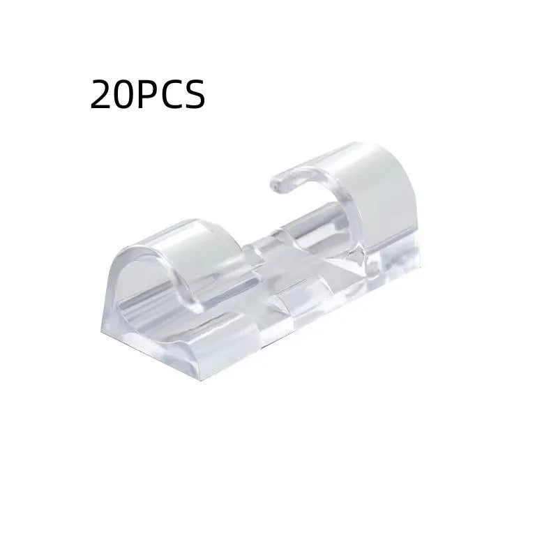 Transparent plastic self-adhesive cable clip holding a white wire against a wall.