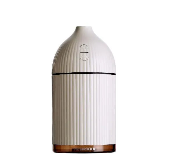 White ultrasonic aromatherapy diffuser with LED light and USB cable on a wooden table