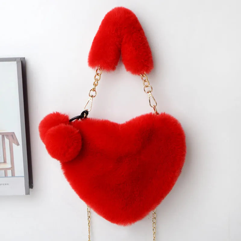 A soft, heart-shaped plush handbag for women in a medium size with a detachable shoulder strap.