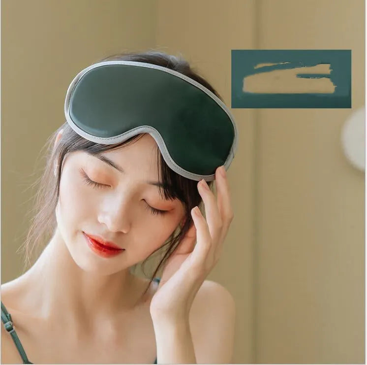 Green portable eye steam massage goggles with USB cable on a table.