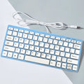 Compact USB wired mini keyboard in black, white, pink, or blue on a desk.