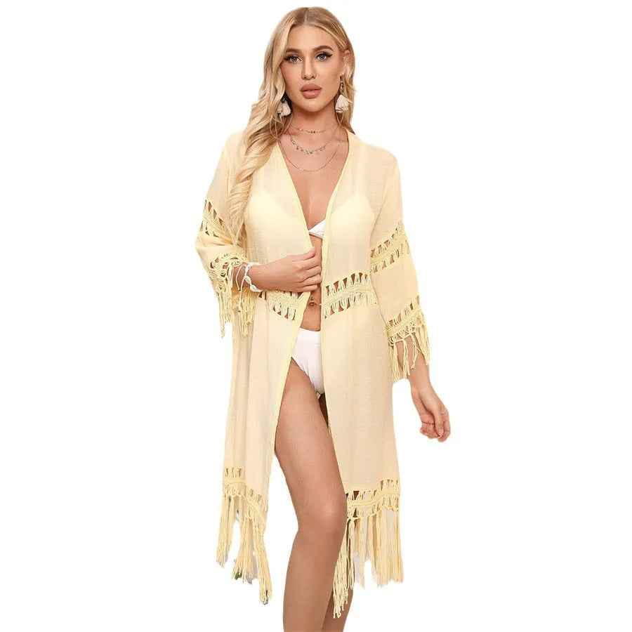 Yellow hand-crocheted women's beach cardigan with tassel detail on a hanger.